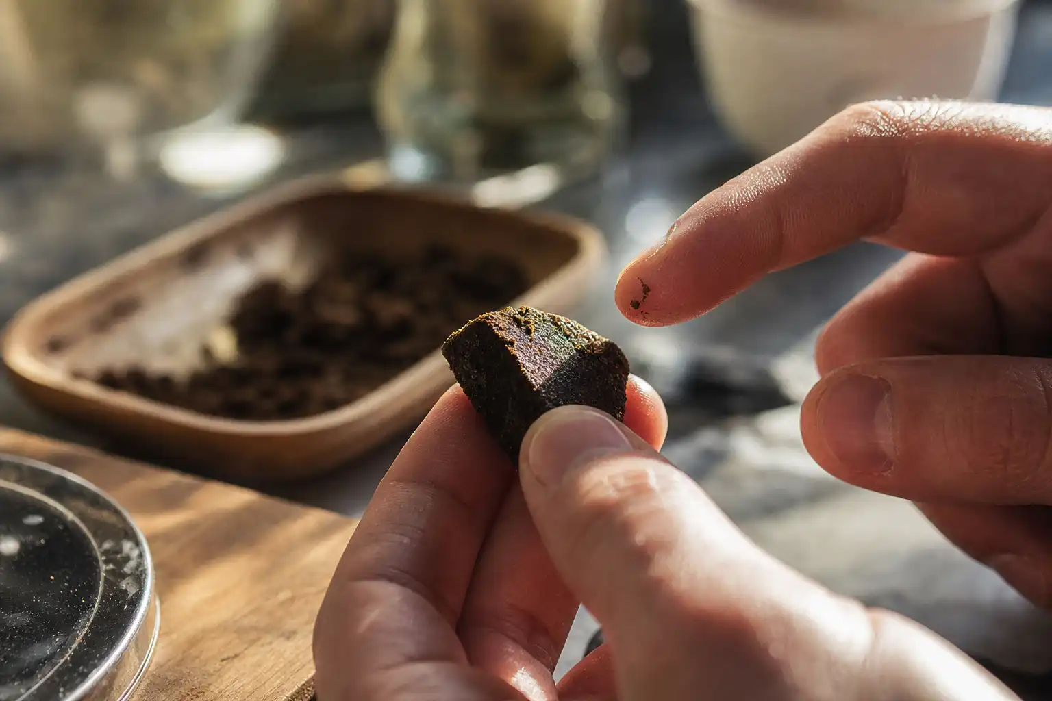 Des mains examinent un objet, autour de résine cbd, dans une cuisine.